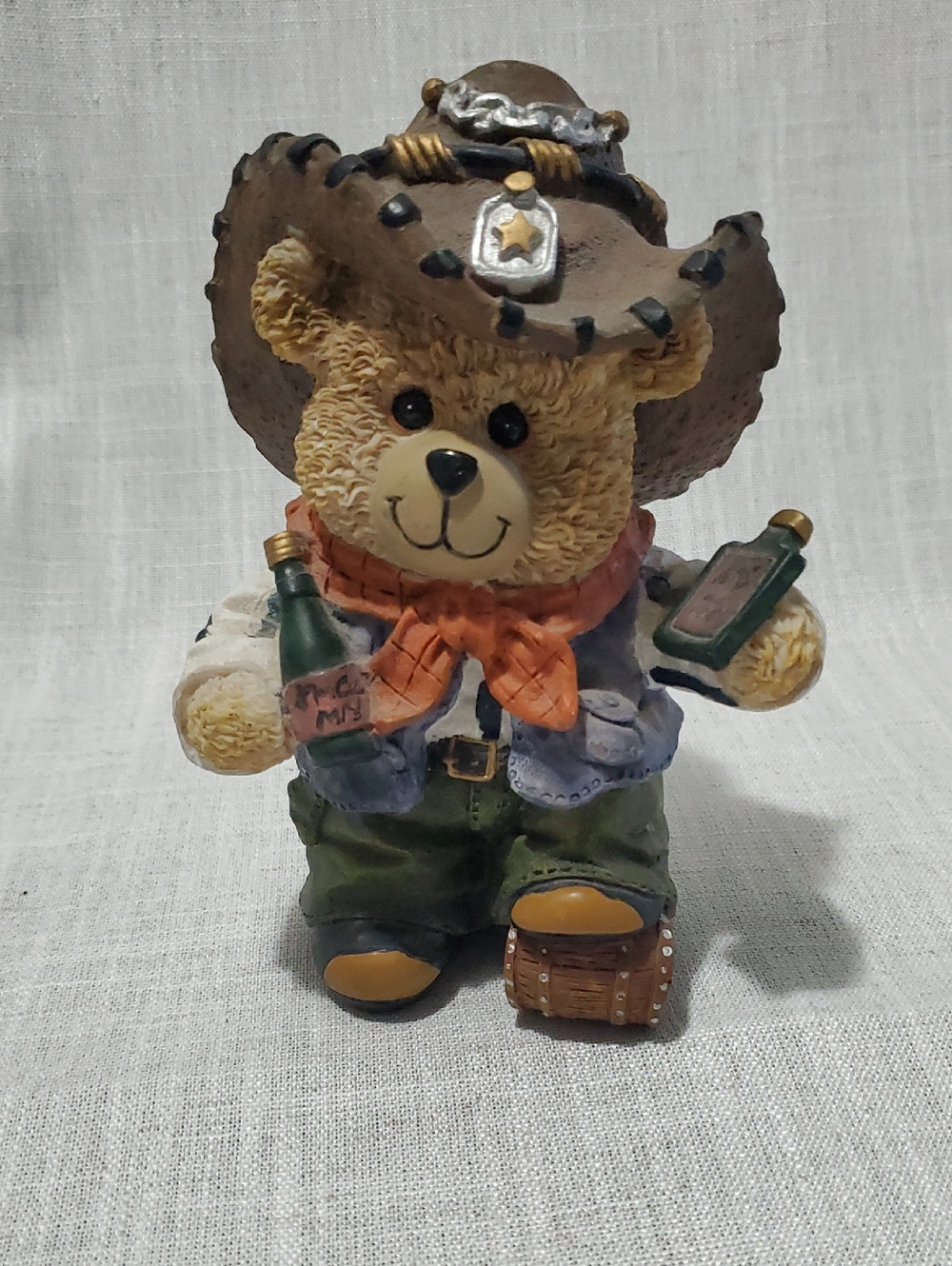 A vintage resin teddy bear figurine dressed as a cowboy.